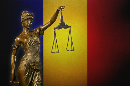 Close-up of a small bronze statuette of Lady Justice before a flag of Romania.の写真素材