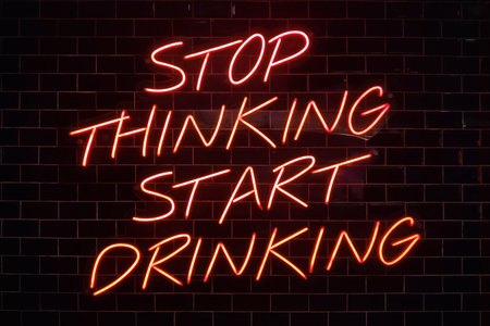 A red neon light shaped into the phrase : Stop thinking start drinking