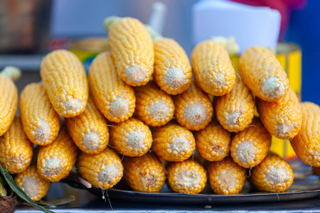 Stack of maize ears ready to by boiled and sold on a market stall.の写真素材