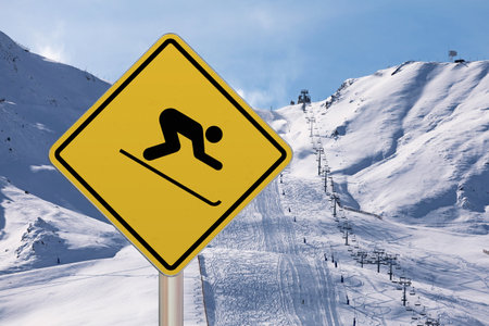 Diamond-shaped crossing sign with yellow background and black border with a skier symbol drawn in the middle.の写真素材