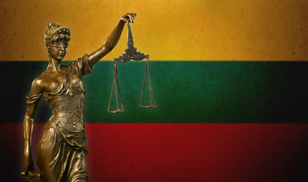 Close-up of a small bronze statuette of Lady Justice before a flag of Lithuania.の写真素材