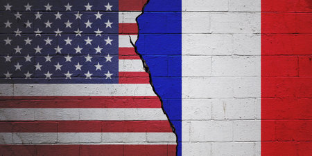 Cracked cinder block wall painted with a flag of the USA on the left and a flag of France on the right.の写真素材