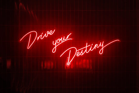 Red neon light shaped into the short phrase : Drive your destiny.
