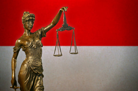 Close-up of a small bronze statuette of Lady Justice before a flag of Indonesia.の写真素材