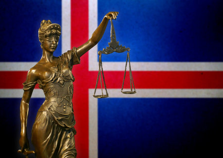 Close-up of a small bronze statuette of Lady Justice before a flag of Iceland.の写真素材