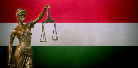 Close-up of a small bronze statuette of Lady Justice before a Hungarian flag.の写真素材