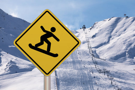 Diamond-shaped crossing sign with yellow background and black border with a snowboarder symbol drawn in the middle.の写真素材
