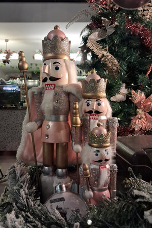 Three pink nutcrackers next to a Christmas tree in a coffee shop window.