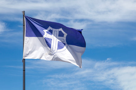 Close-up on the flag of the German town of HÃ¼nfeld waving on top of a pole.