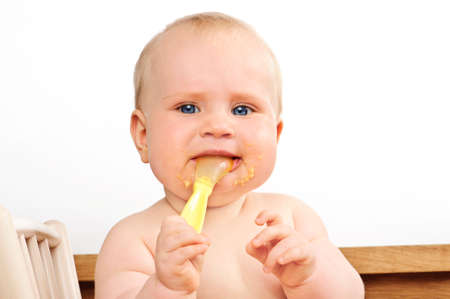 Baby, less than a year old, chews on a rubber spoon while eating, in an attempt to alleviate teething pains.の写真素材