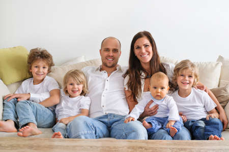 Four brothers and their parents sitting on a sofaの写真素材