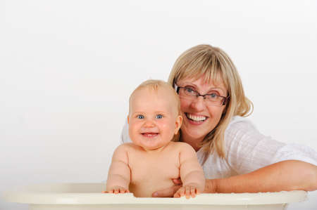 Grandmother bathes her granddaughter  Both are looking at camera and smiling  Babyの写真素材