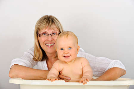 Grandmother bathes her granddaughter  Both are looking at camera and smiling  Babyの写真素材