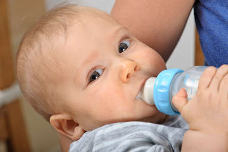 Seven month old baby boy bottle feeding in his motherの写真素材