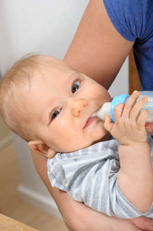 Seven month old baby boy bottle feeding in his motherの写真素材