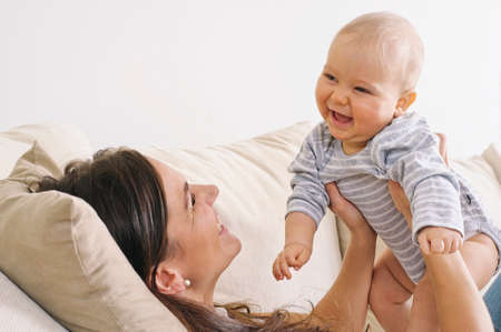 Mother lifts her baby son in the air  Sheの写真素材