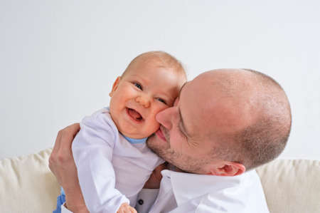 Father holding and playing with his infant sonの写真素材