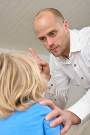 A man scolds a young child indoorsの写真素材
