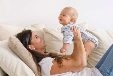 Mother lifts her baby son in the air  Sheの写真素材
