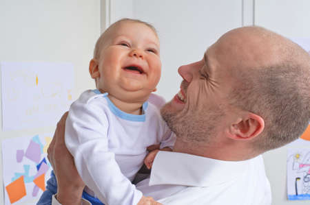 Father holding and playing with his infant sonの写真素材