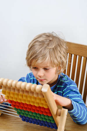A young boy learns to count using an abacusの写真素材
