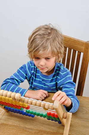 A young boy learns to count using an abacusの写真素材
