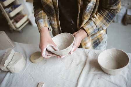Woman's hands making clay bowl In pottery studioの写真素材