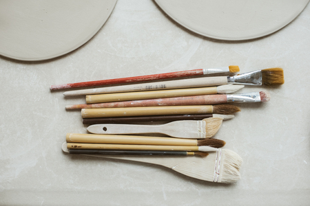 Top view on different rustic brushes with wooden holders for ceramic and workpieces for handmade platesの写真素材