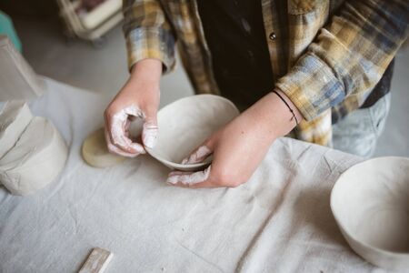Woman's hands making clay bowl In pottery studioの写真素材