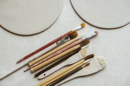 Top view on different rustic brushes with wooden holders for ceramic and workpieces for handmade platesの写真素材