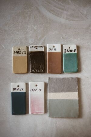 Top view on colored glazed ceramic samples on grey table in workroomの写真素材