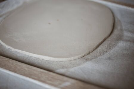 Rolled out piece of clay for modeling ceramic plate on big table with industrial fabric in workshopの写真素材
