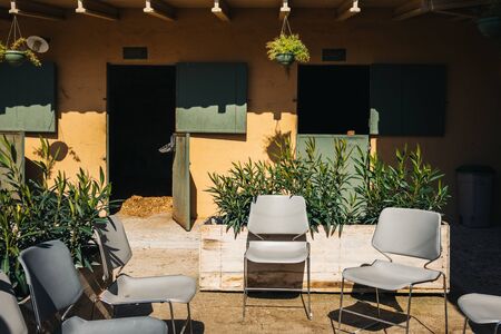 Empty stable for horses with yellow wall and grey chairs on ranchの写真素材