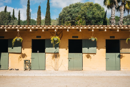 Empty stables for horses with yellow wall and green doors on ranchの写真素材