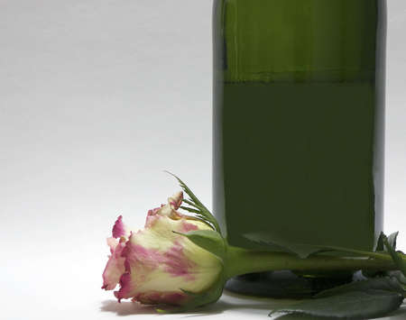 Photo of a pink and white rose next to a bottle of champagneの写真素材