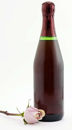 Photo of a bottle of red champagne next to a pink roseの写真素材