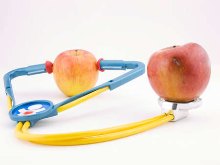 Photo of an apple using a stethoscope on another apple with a bad spot on itの写真素材