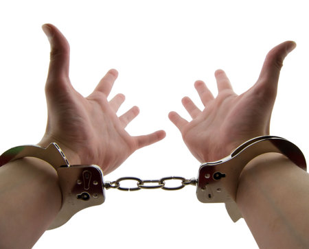 Photo of a mans wrists handcuffed with hands out stretched, isolated on white