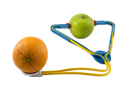 Photo of a apple wearing a stethoscope, checking an orange, isolated on whiteの写真素材