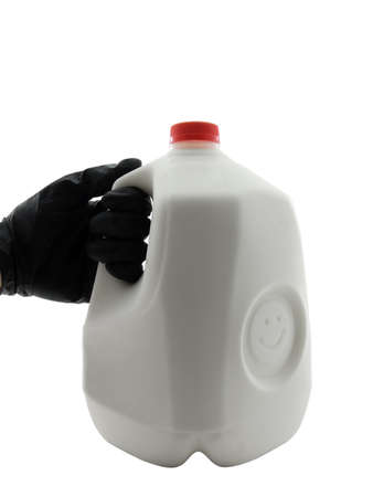 Black gloved hand holding a jug of milkの写真素材