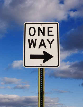 One way sign with a cloudy blue sky background