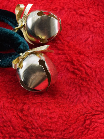 Gold christmas bells on a red plush fabricの写真素材