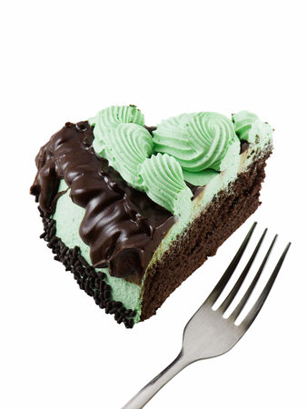 Slice of mint chocolate cake with a fork isolated on whiteの写真素材