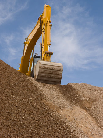 Excavator on top of a dirt mound