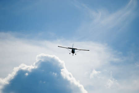 Airplane flying off into the cloudsの写真素材