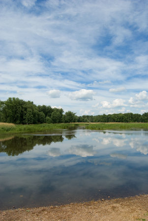 Beautiful summer day at a lake with clouds reflecting of the waters surface