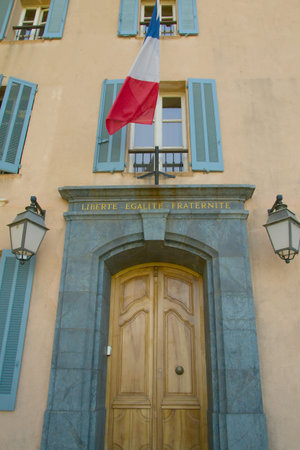 The entrance door to the building  Above the door hangs a French flag and the inscription Liberte,...