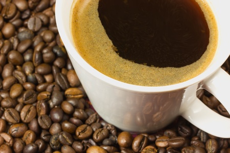 Detailed view of a cup of coffee with a coffe bean in the background の写真素材