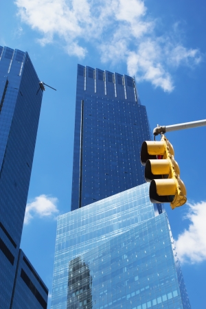Modern blue office buildings with yellow traffic light in the foreground  Blue sky in the background のeditorial素材