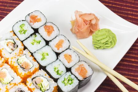 Maki Sushi on the white plate with wasabi and ginger  With chopsticks の写真素材